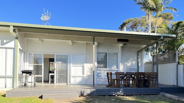 A covered patio with a table and chairs, a sliding glass door, and a satellite dish. - 'The Savoy'. Central home with pool. Pet friendly (Port Macquarie)