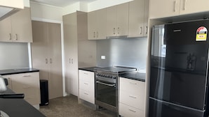 A modern kitchen with stainless steel appliances, including a refrigerator, stove, and oven. There are white cabinets and a black countertop. - 'The Savoy'. Central home with pool. Pet friendly (Port Macquarie)