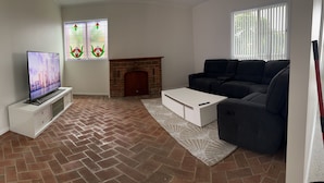 A living room with a TV, fireplace, sofa, and patterned rug. - 'The Savoy'. Central home with pool. Pet friendly (Port Macquarie)
