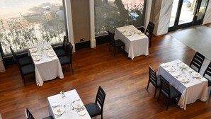 En restaurant med flere borde dækket til spisning, med hvide duge og sorte stole.