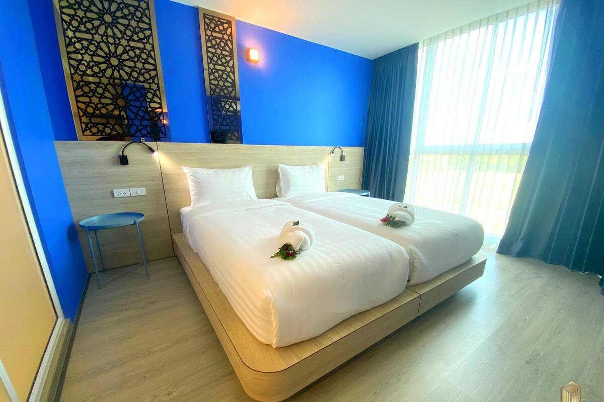 Una habitación de hotel con una cama grande, una mesita pequeña y un panel decorativo en la pared.