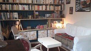 A living room with a bookshelf, a white sofa, a small table, and a red rug.