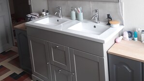 A bathroom with a double sink vanity, a large mirror, and a cabinet with drawers.