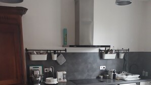 A modern kitchen with white cabinetry, a wooden dining table, and a hanging light fixture.