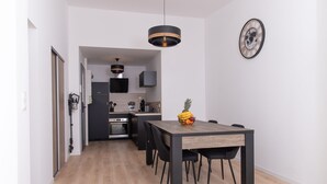 A modern kitchen with dark cabinetry, a wooden dining table, and a fruit bowl.