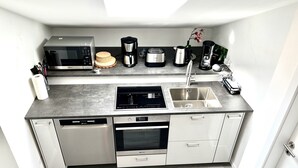 Een kleine keuken met een vaatwasser, oven, magnetron en een koffiezetapparaat.