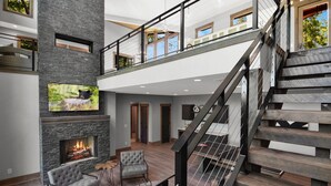 Ein großzügiger Wohnbereich mit Kamin, einer Treppe und einem Balkon.