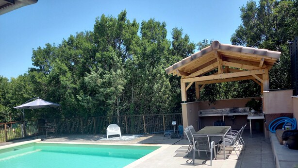 Uima-allasalue, jossa on puinen pergola, grillauspaikka ja katettu oleskelualue.