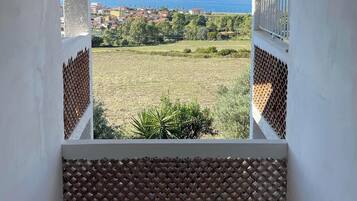 Un balcone con vista su una cittadina costiera e un cielo sereno.