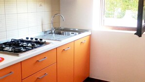 A kitchen with orange cabinets, a white countertop, a stainless steel sink, and a gas stove.