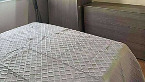 A bedroom with a bed, a wardrobe, a mirror, and a window with curtains.