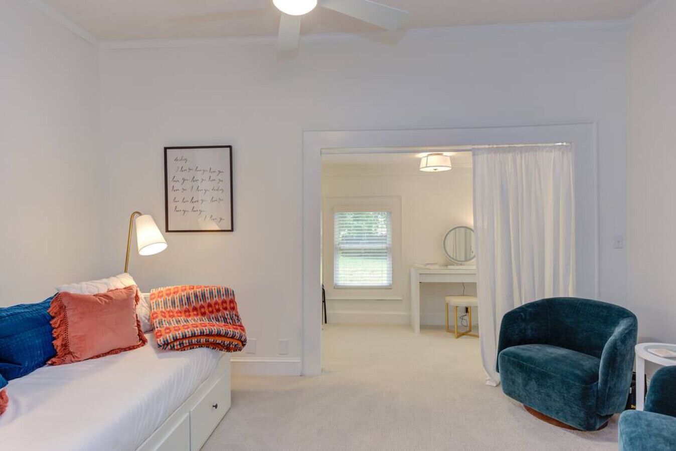 A bedroom with a bed, a desk, a chair, and a bathroom visible through an open door.