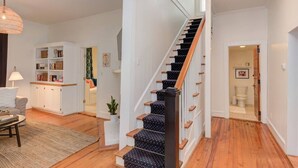 Un escalier avec des marches en bois et des contremarches recouvertes de moquette noire, menant à un palier avec une porte blanche.