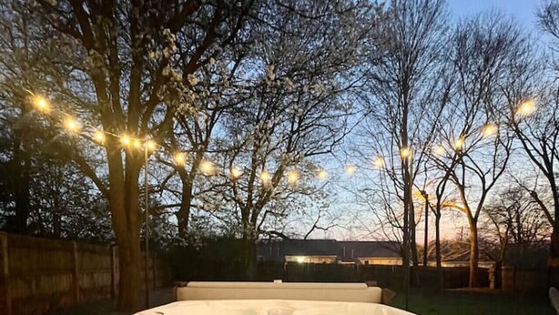 Un bain à remous installé à l’extérieur, agrémenté de guirlandes lumineuses.