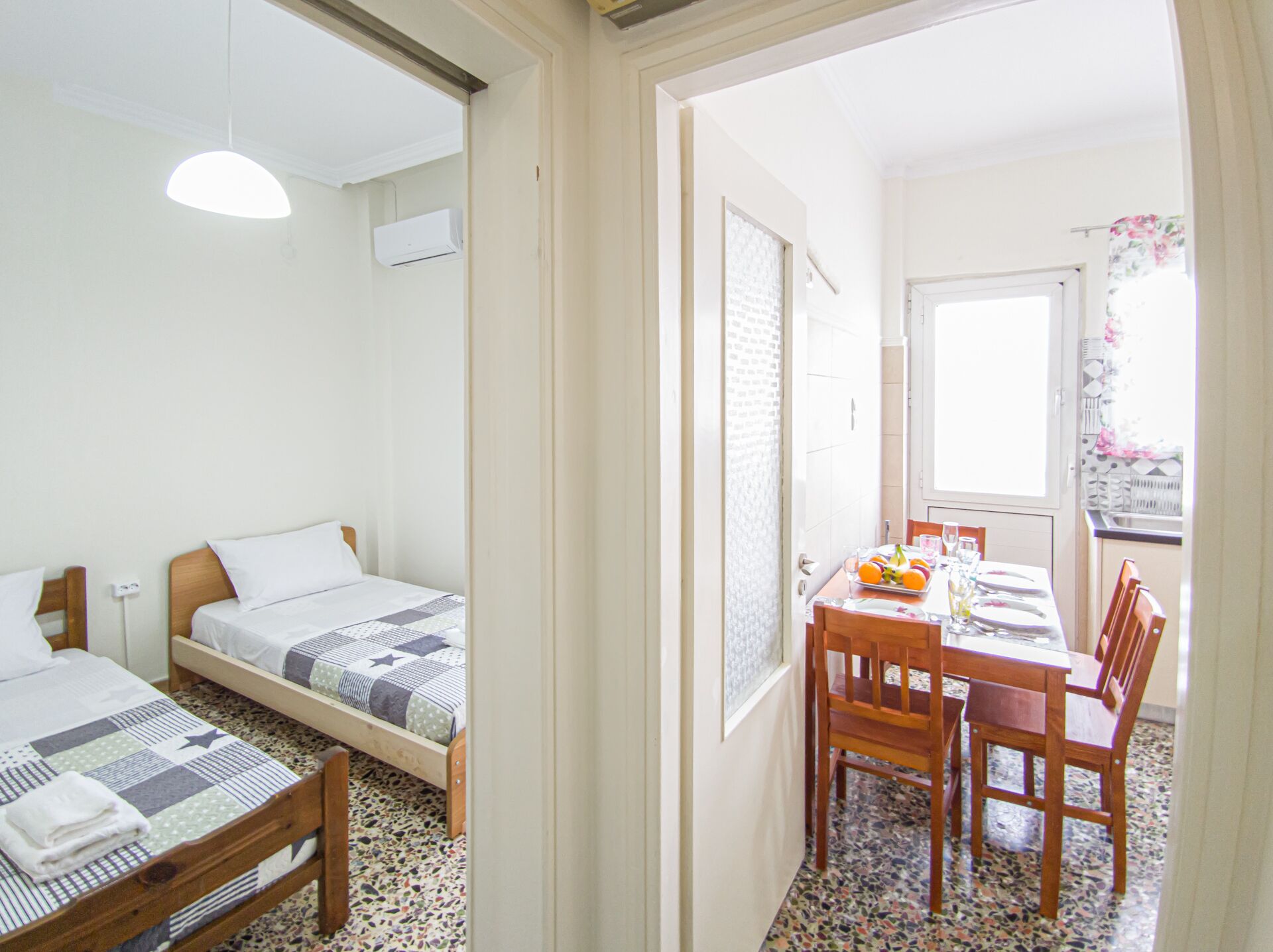 Een slaapkamer met twee bedden, een kleine tafel met stoelen, een raam met uitzicht en een airconditioning.