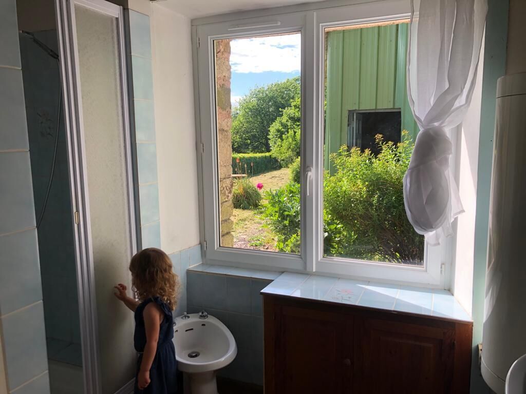 Une salle de bain avec une fenêtre, un lavabo et une douche.