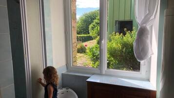 Une salle de bain avec une fenêtre, un lavabo et une douche.