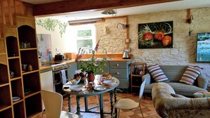 A cozy kitchen with a dining table set, a sofa, and a TV. - A cosy riverside cottage in the Devon countryside on the Edge of Dartmoor. (Yelverton)