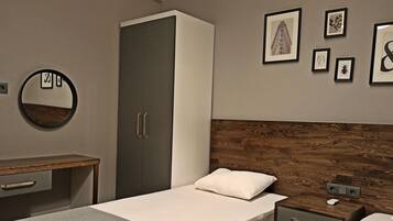 Een moderne slaapkamer met een houten hoofdbord, een bed met een wit kussen, een nachtkastje, een kledingkast en ingelijste foto's aan de muur.