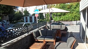 An outdoor seating area with wooden furniture and a metal fence. - Merve Apart Otel (Alanya)
