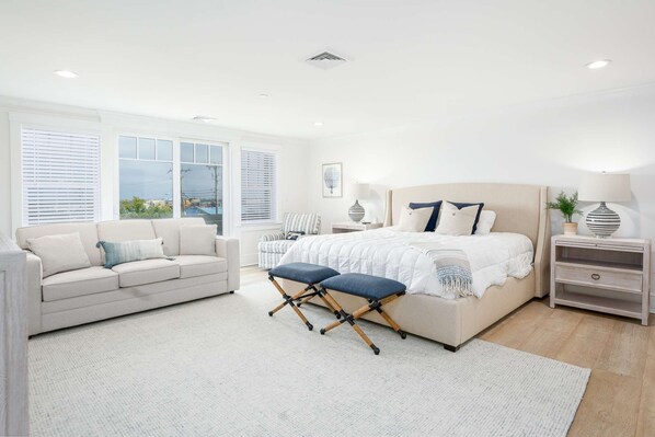 A spacious bedroom with a large bed, a sofa, and a chair.