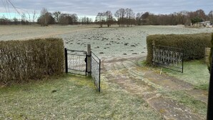 A rural landscape with a gate leading to a field covered in frost. - Hobbithaus resort (Eggesin)