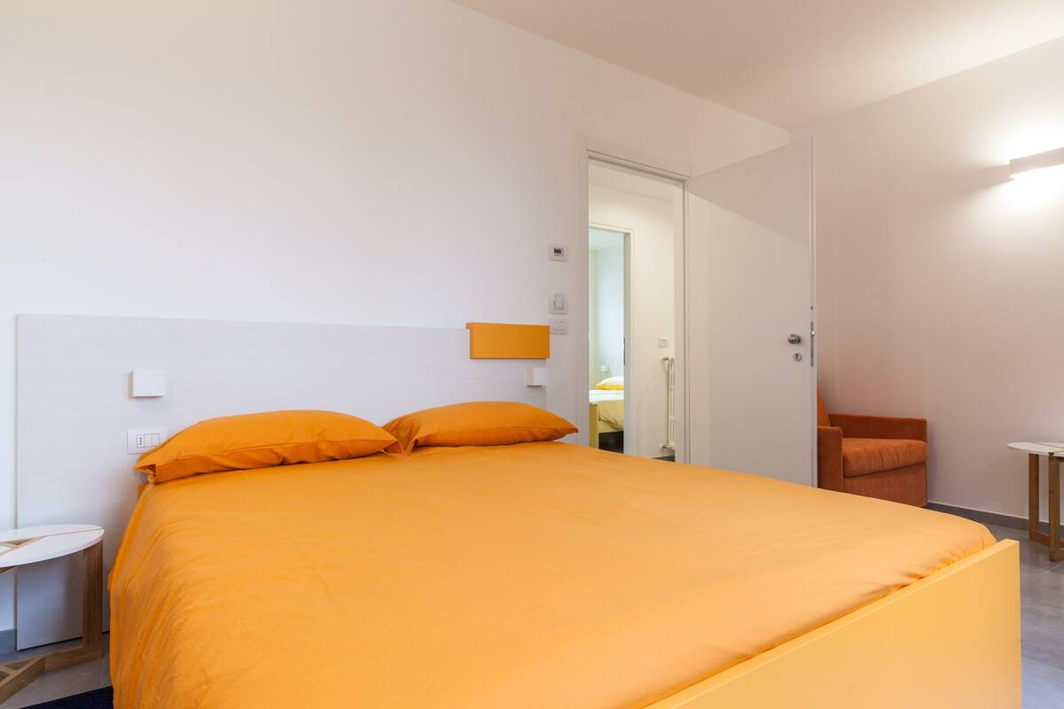 A room with a large bed, a small table, and a chair.
