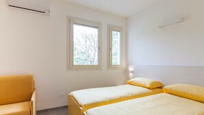 A room with two beds, a sofa, and an air conditioning unit.