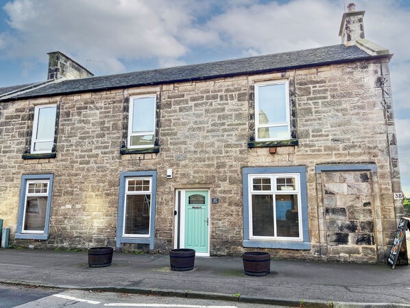 A stone building with multiple windows and doors, including a green door and a number 40 sign.