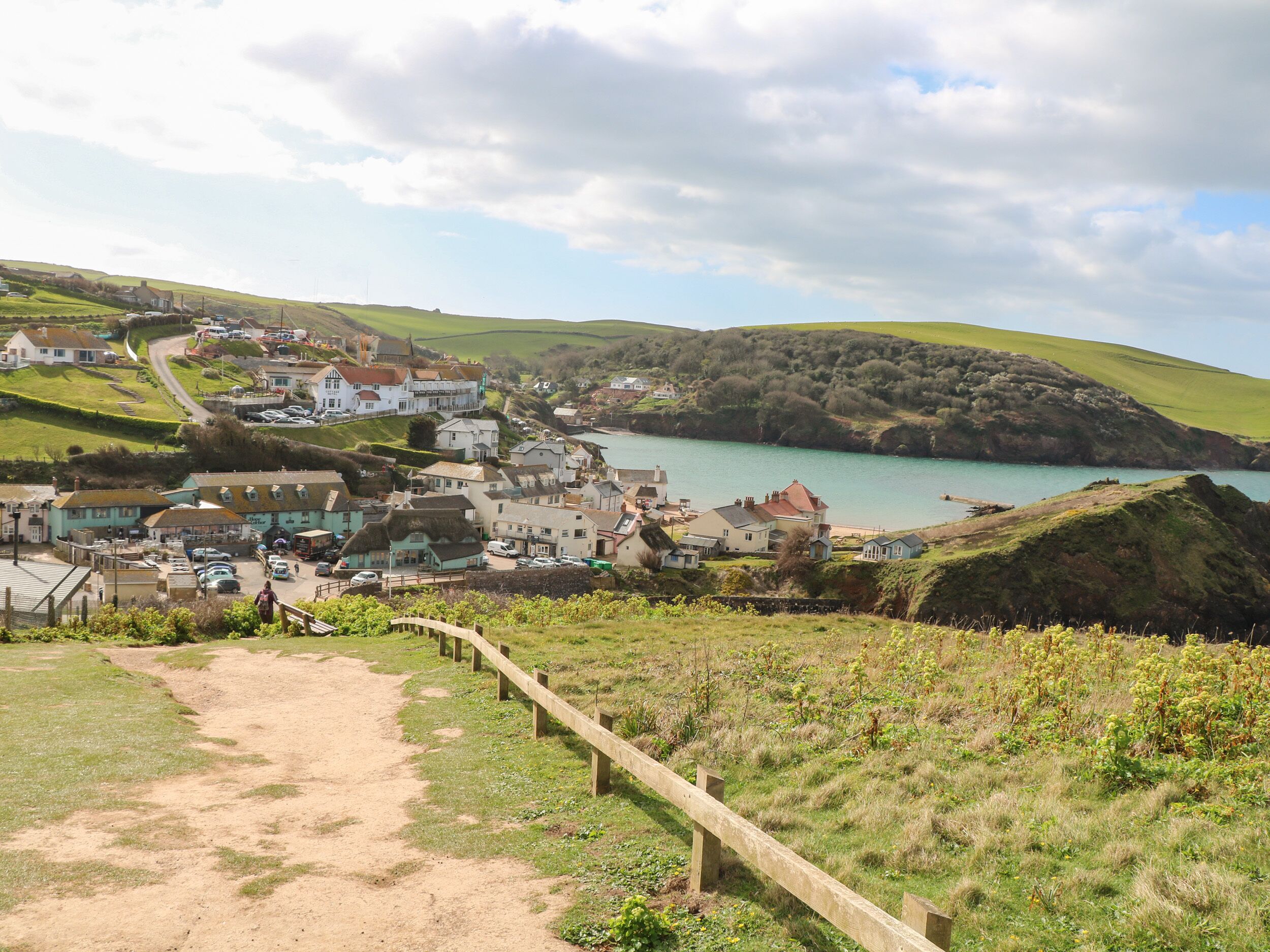 A coastal village with houses, a path, and a view of the sea.
