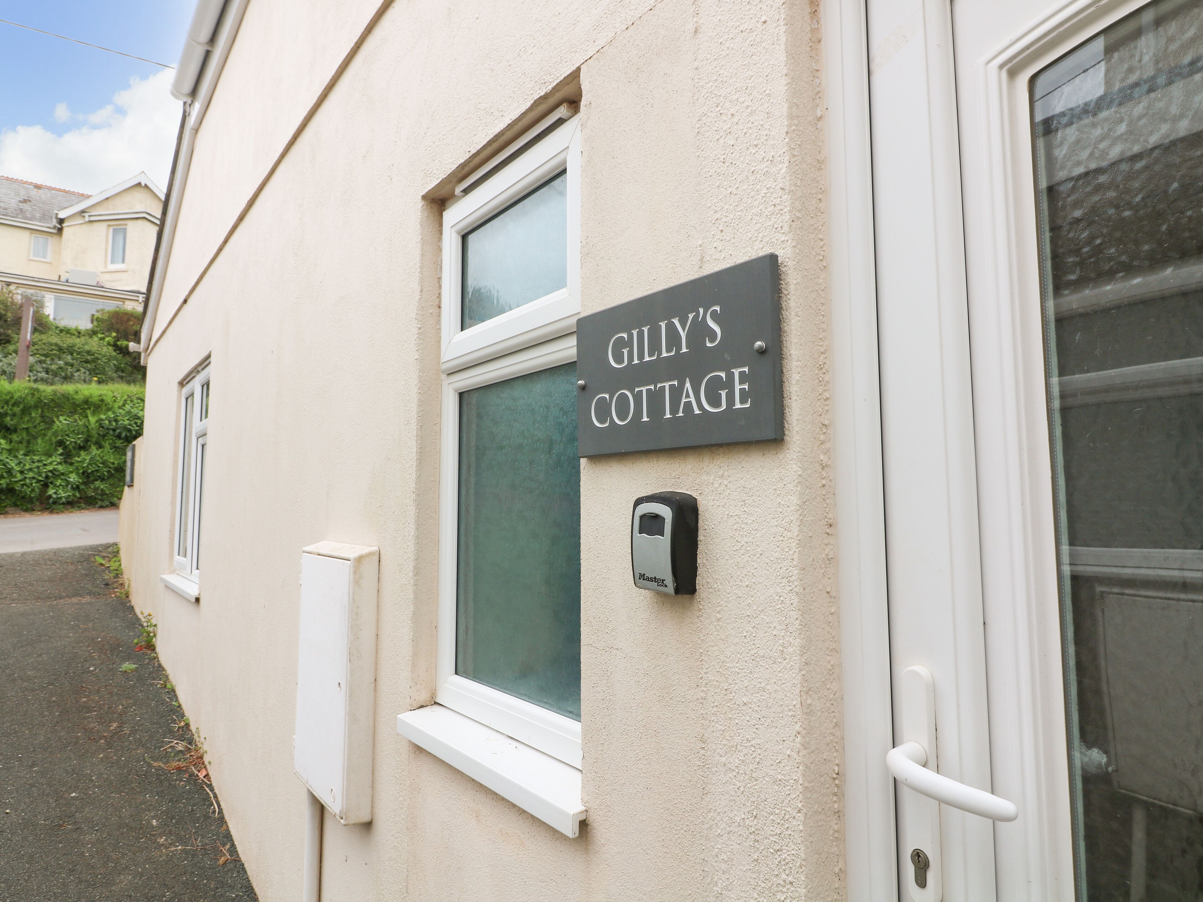 Un edificio con un'insegna che riporta "Gilly's Cottage" e un pulsante del campanello.
