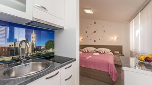 A modern kitchen with a stainless steel sink and a mural of a cityscape. - Apartments Maza (Zadar)