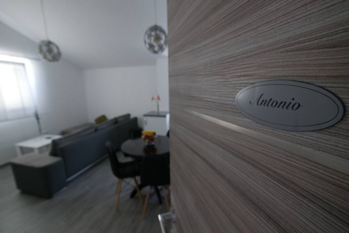 Uma cozinha moderna com área de refeições, uma placa com o nome "Antonio" e vista para a sala de estar.
