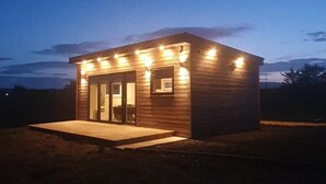 Une petite cabane en bois avec une véranda, une porte et une fenêtre.