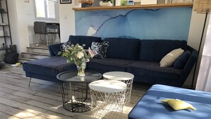 A modern living room with a blue sofa, two round tables, and a vase of flowers.