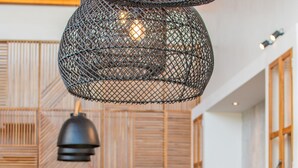 Una cocina moderna con una mesa de comedor de madera, una lámpara colgante negra y un frutero sobre la mesa.