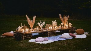 A rustic outdoor dining setup with wooden tables, candles, and decorative elements on a grassy field. - Mokrice Castle Estate (Brezice)