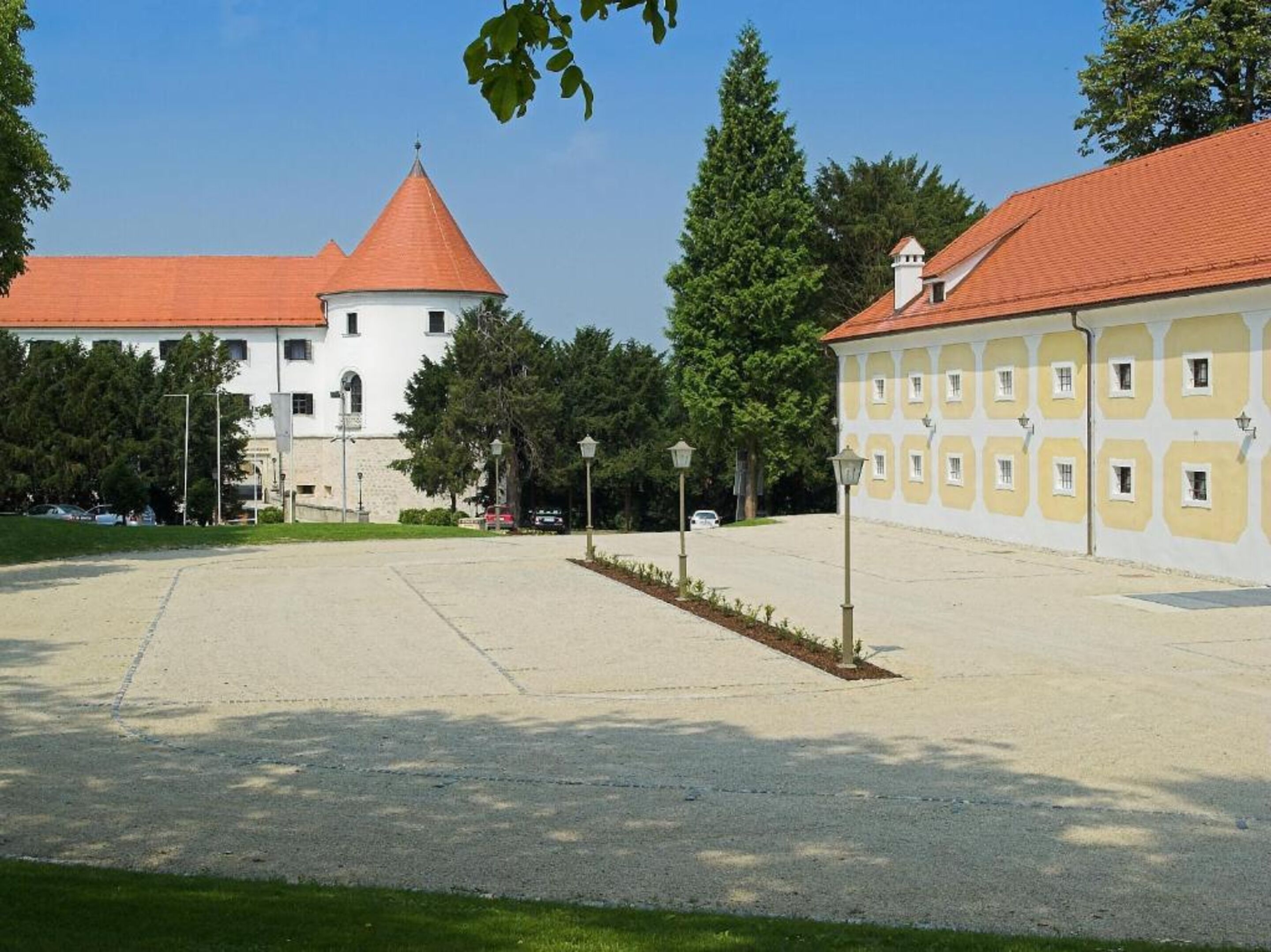 Une cour avec un bâtiment blanc doté d’un toit rouge et un bâtiment jaune avec de nombreuses fenêtres.