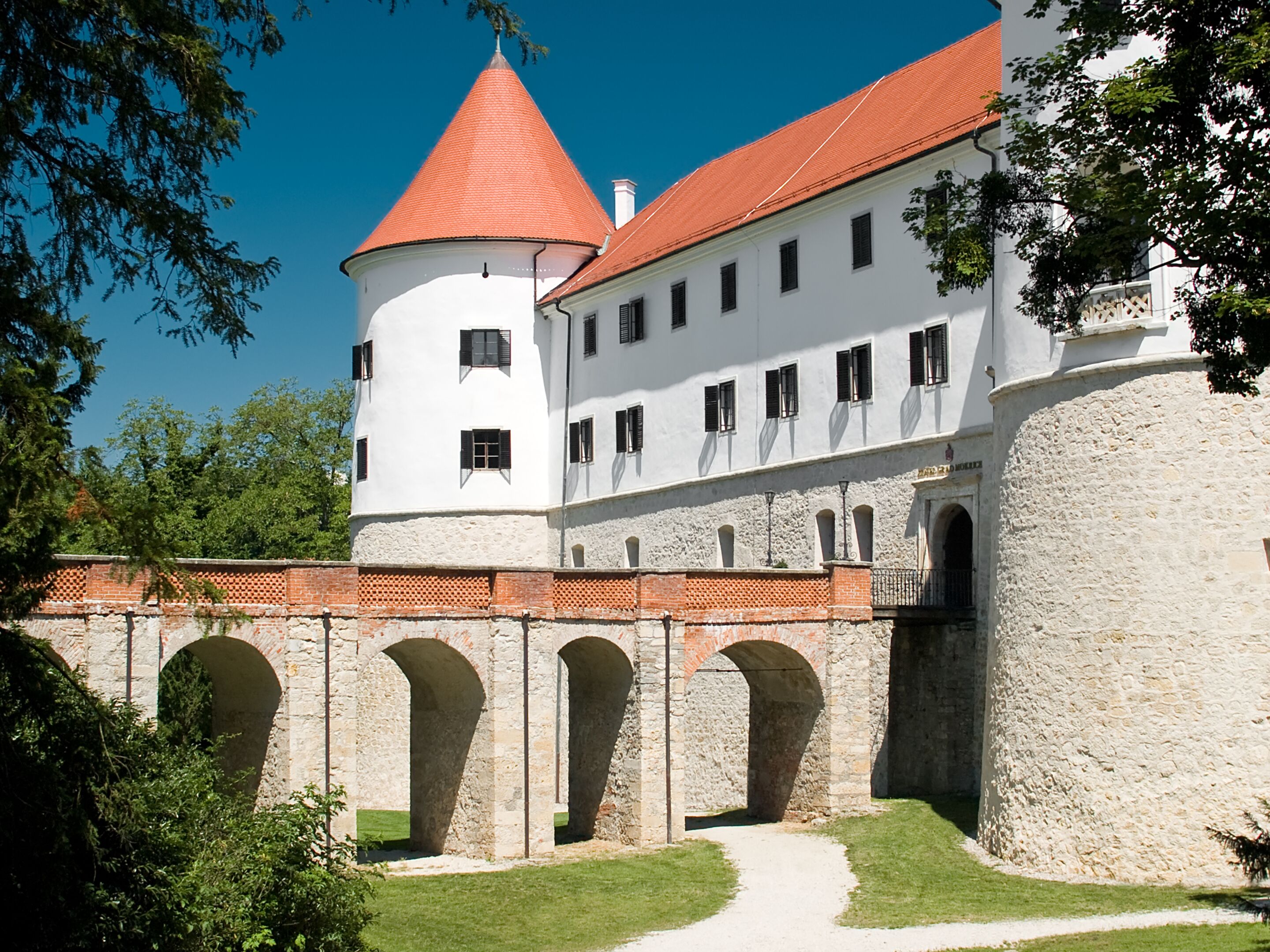 A historic building with a central tower, multiple windows, and a paved courtyard.