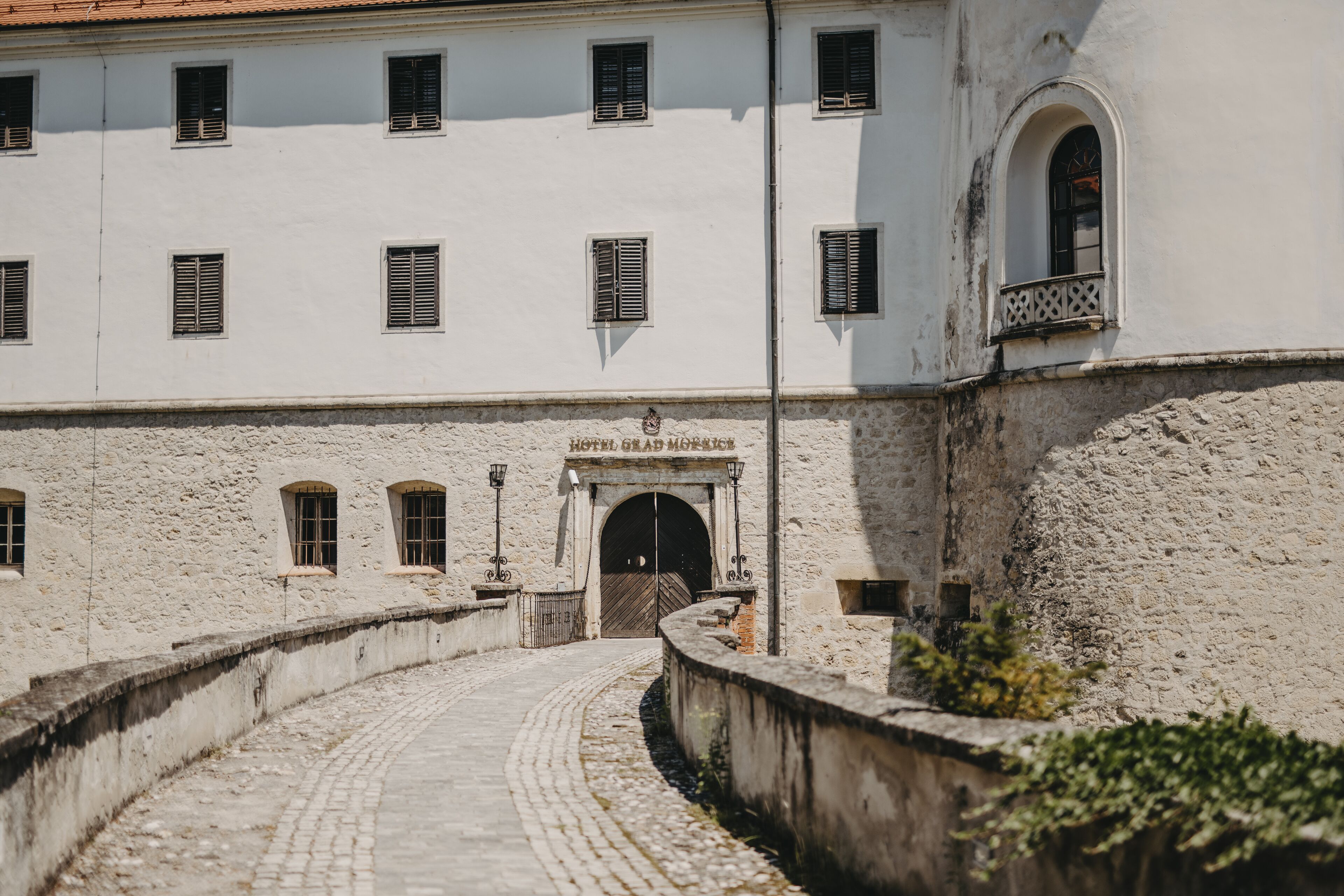 A historic building with a central entrance, arched doorway, and multiple windows with shutters.