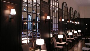 A long, dimly lit room with rows of tables and chairs, each with a lamp. Large windows with arched tops allow natural light to enter. - Mokrice Castle Estate (Brezice)