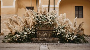 A stone bench with a floral arrangement in front of a building with arched windows. - Mokrice Castle Estate (Brezice)