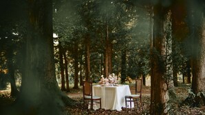 A table set for two in a forest with a white tablecloth and floral centerpiece. - Mokrice Castle Estate (Brezice)