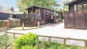 A wooden cabin with a porch, a small attached shed, and a fenced yard. - Robin's Nest (Keswick)