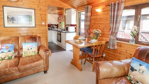 A cozy cabin interior with wooden walls, a dining area, and leather sofas with decorative pillows. - Robin's Nest (Keswick)
