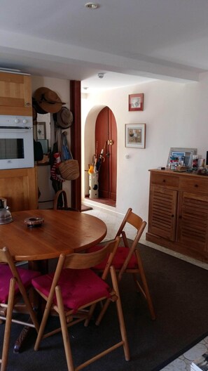 Una cocina acogedora con armarios de madera, una mesa de comedor con sillas y un refrigerador pequeño.
