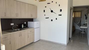 A modern kitchen with wooden cabinets, a white refrigerator, a built-in sink, and a wall clock.
