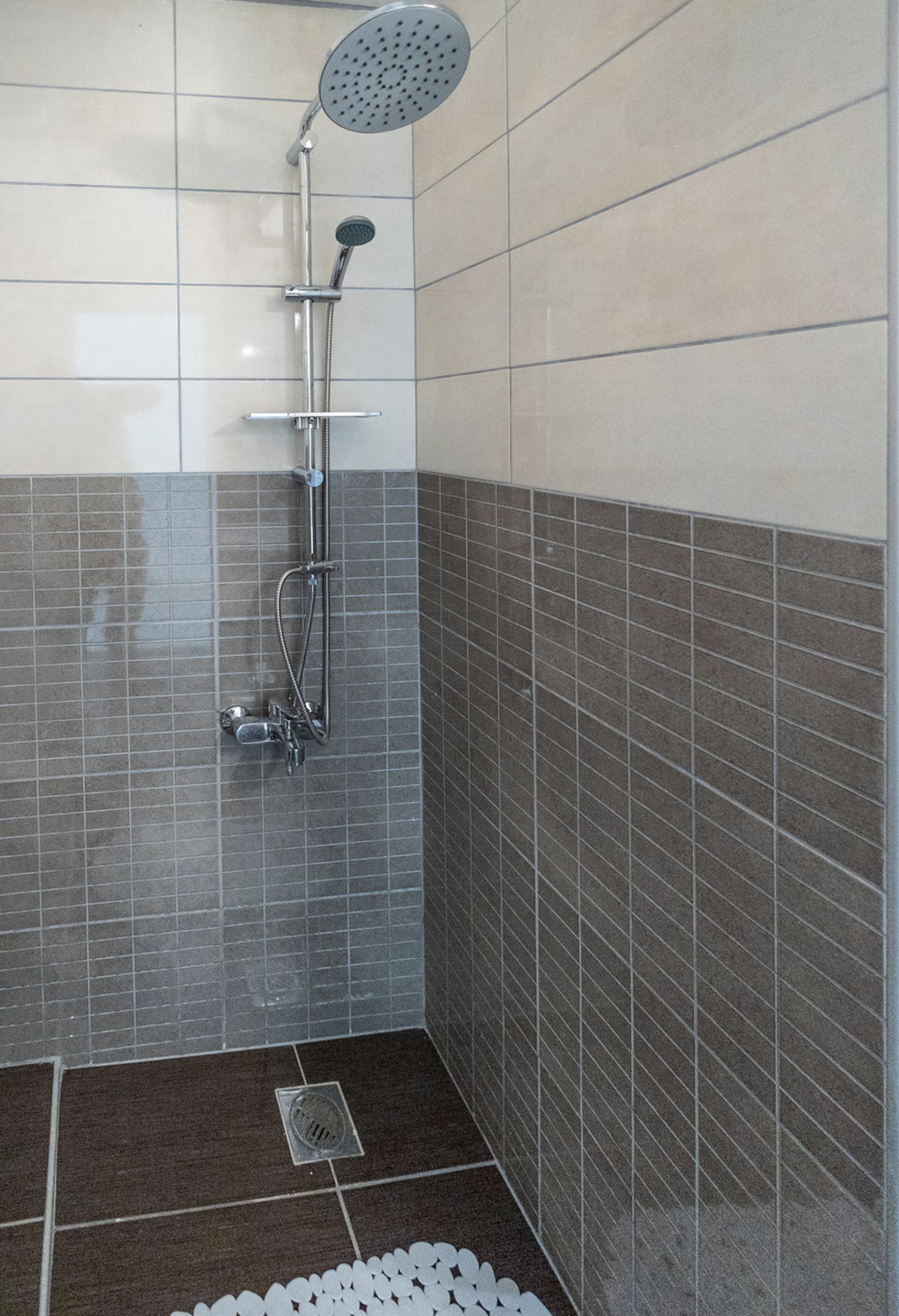 A shower with a handheld showerhead and a wall-mounted faucet.