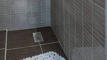 A shower with a handheld showerhead and a wall-mounted faucet.