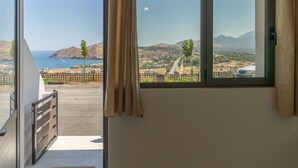 A room with a large window overlooking a coastal landscape, including a mountain and a body of water.